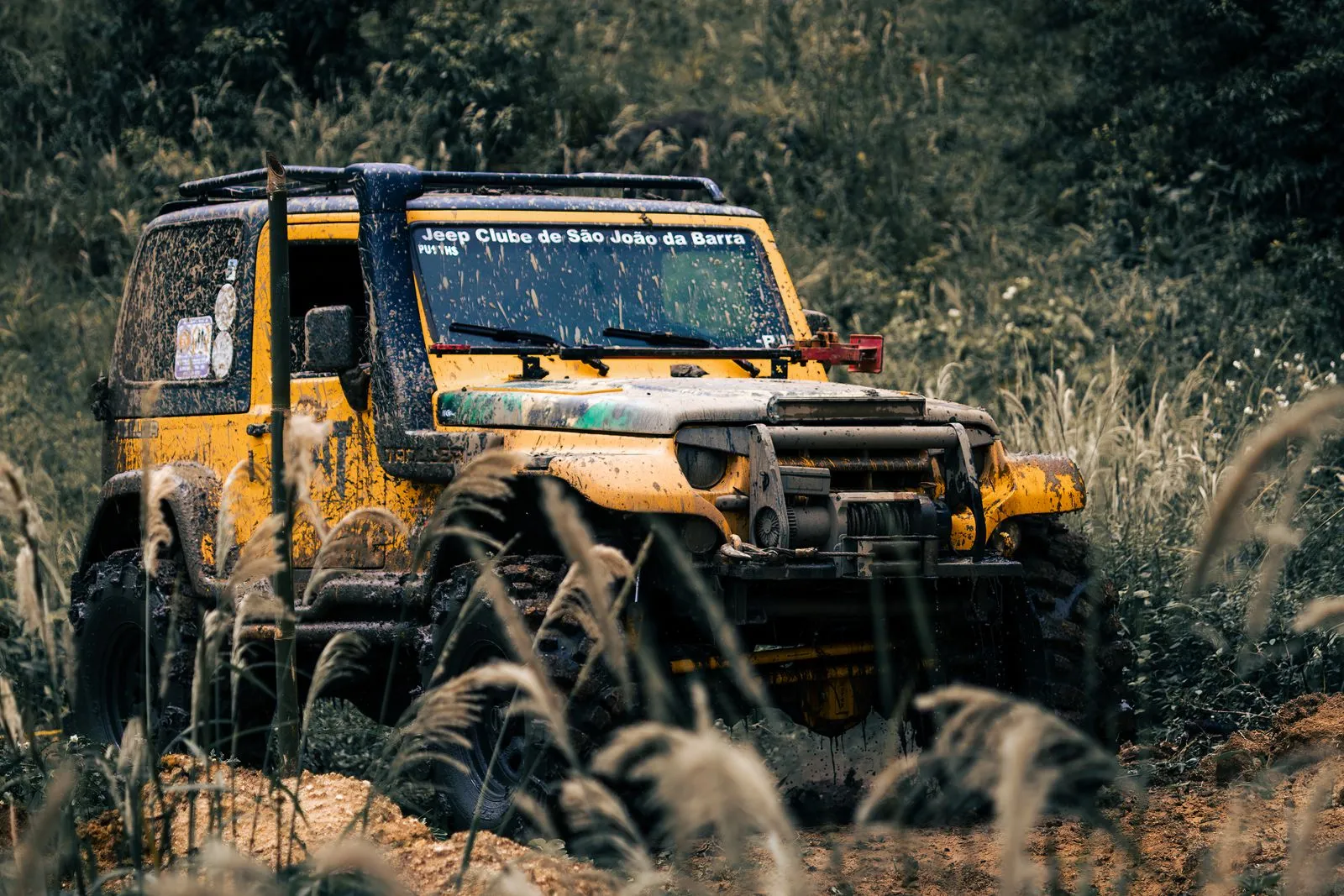 Yellow SUV on a muddy off-road path, showcasing rugged adventure and exploration.